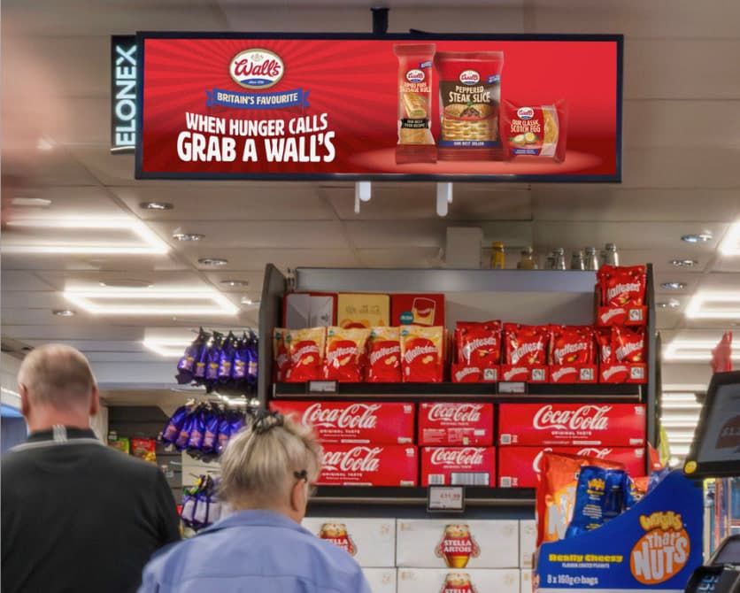 A screen hung from the ceiling above the aisle playing creative over the shop floor