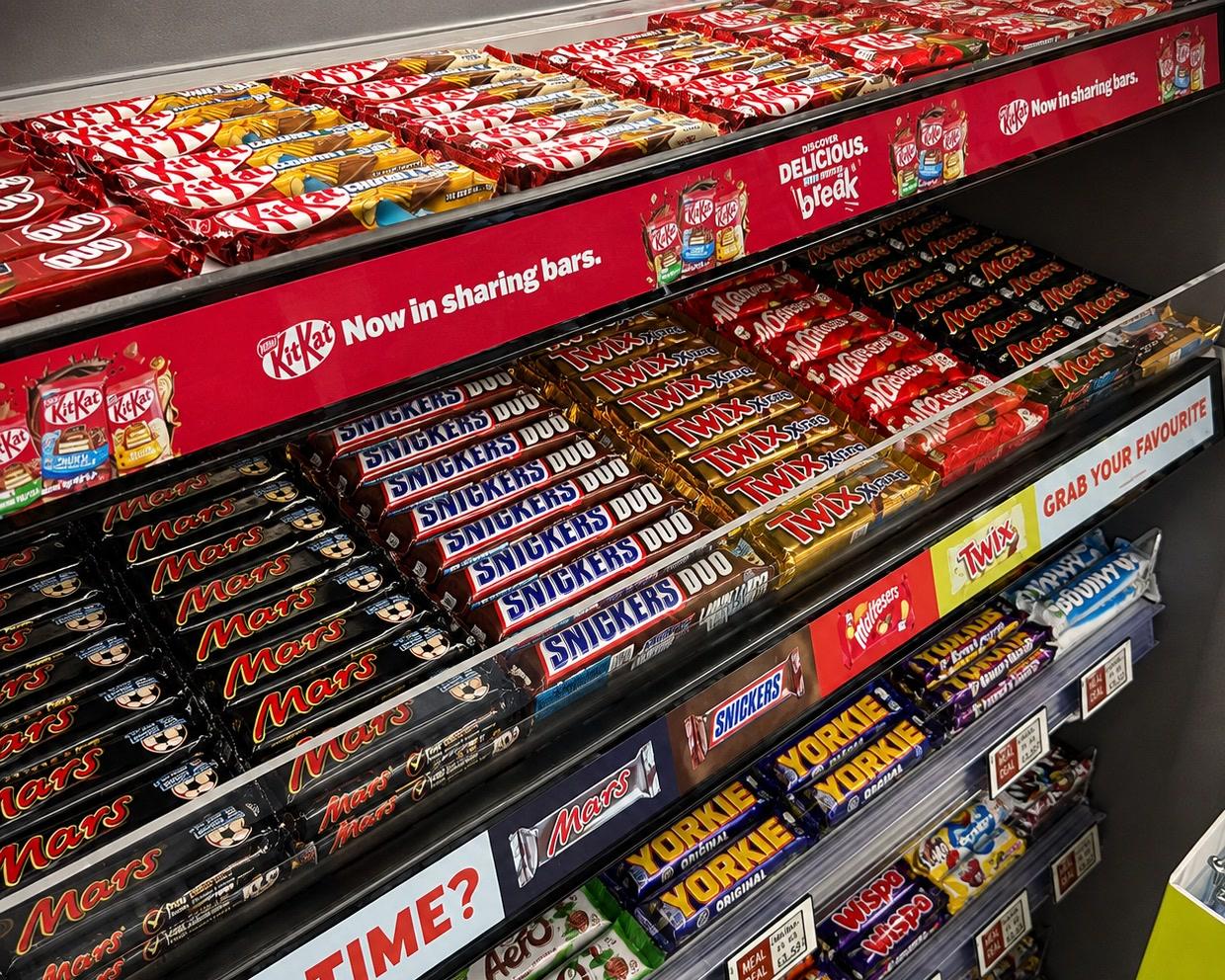 Lit digital rails running along the shelf edges of a confectionery fixture